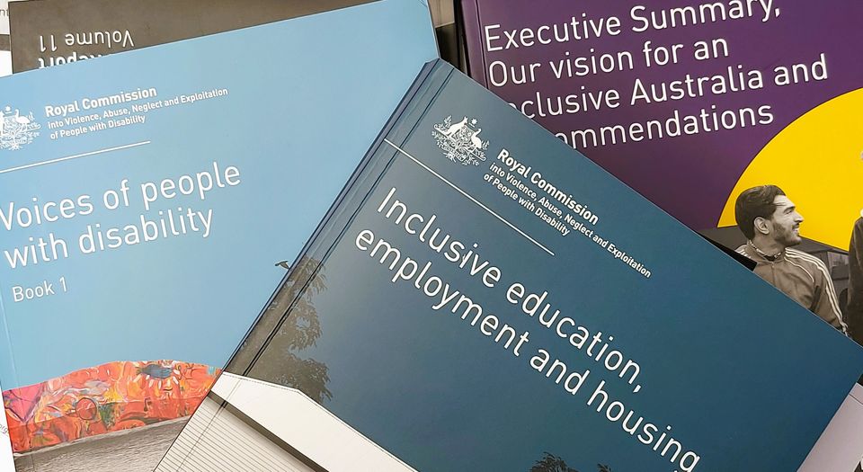 Three volumes of the Disability Royal Commission final report piled on top of each other